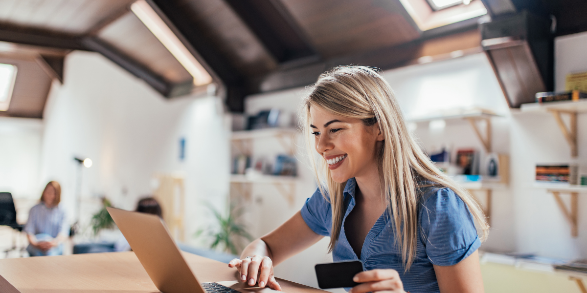 blonde woman sitting at her laptop and smiling