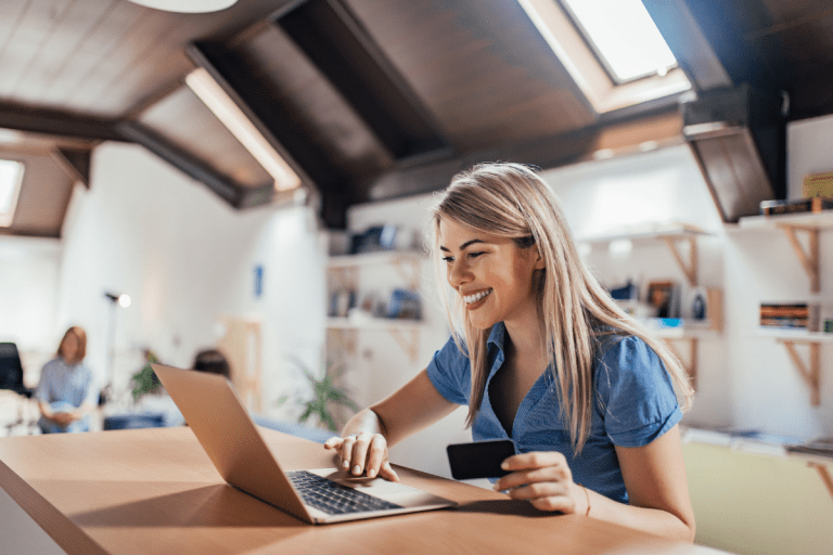 blonde woman sitting at her laptop and smiling